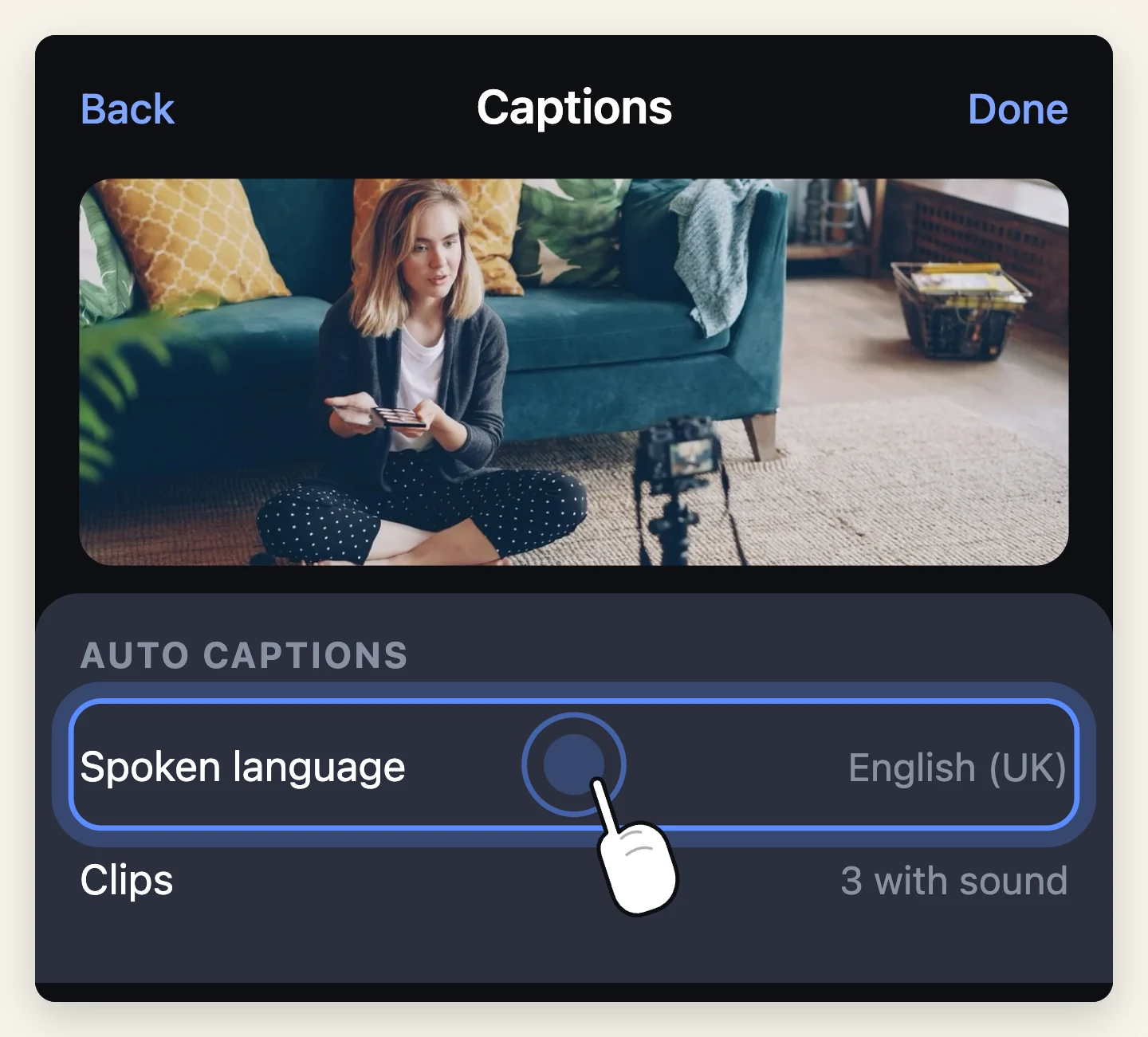 The auto-captions panel over a still of someone talking to a camera on a tripod, with the Spoken language row set to English and being tapped.
